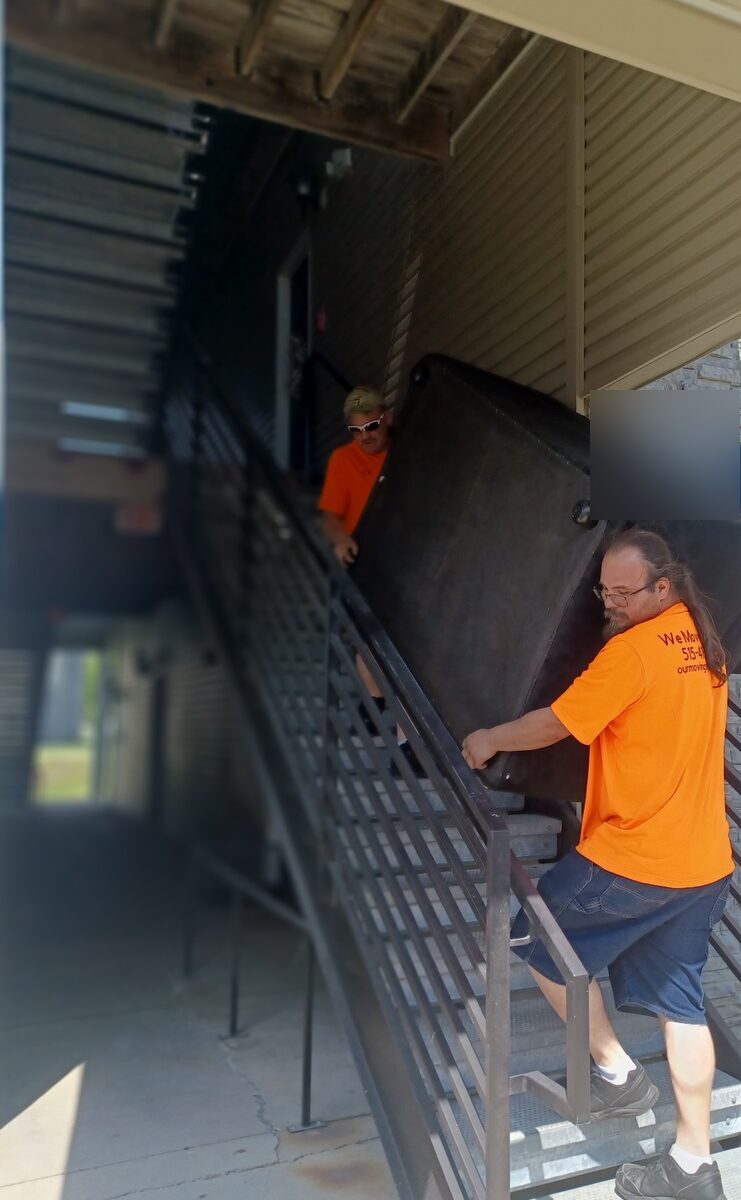 We Move You crew carrying bulky furniture down apartment stairs