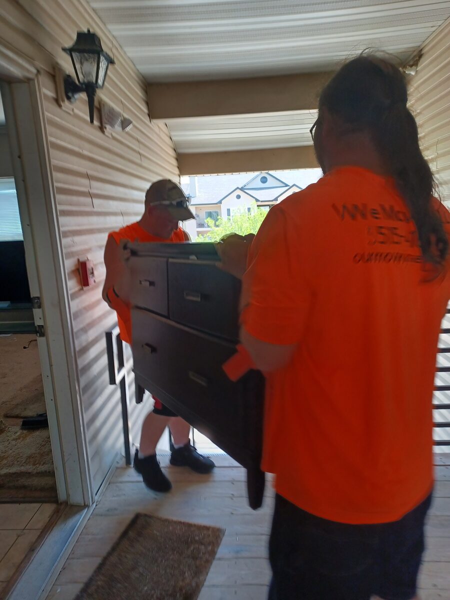 We Move You crew carrying a dresser through a doorway