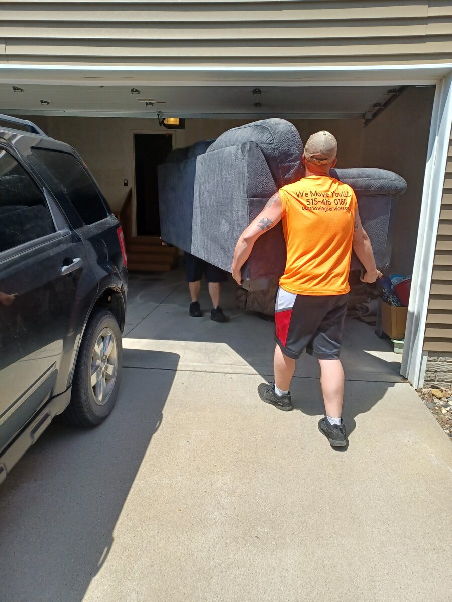 We Move You crew carrying a sofa from a garage